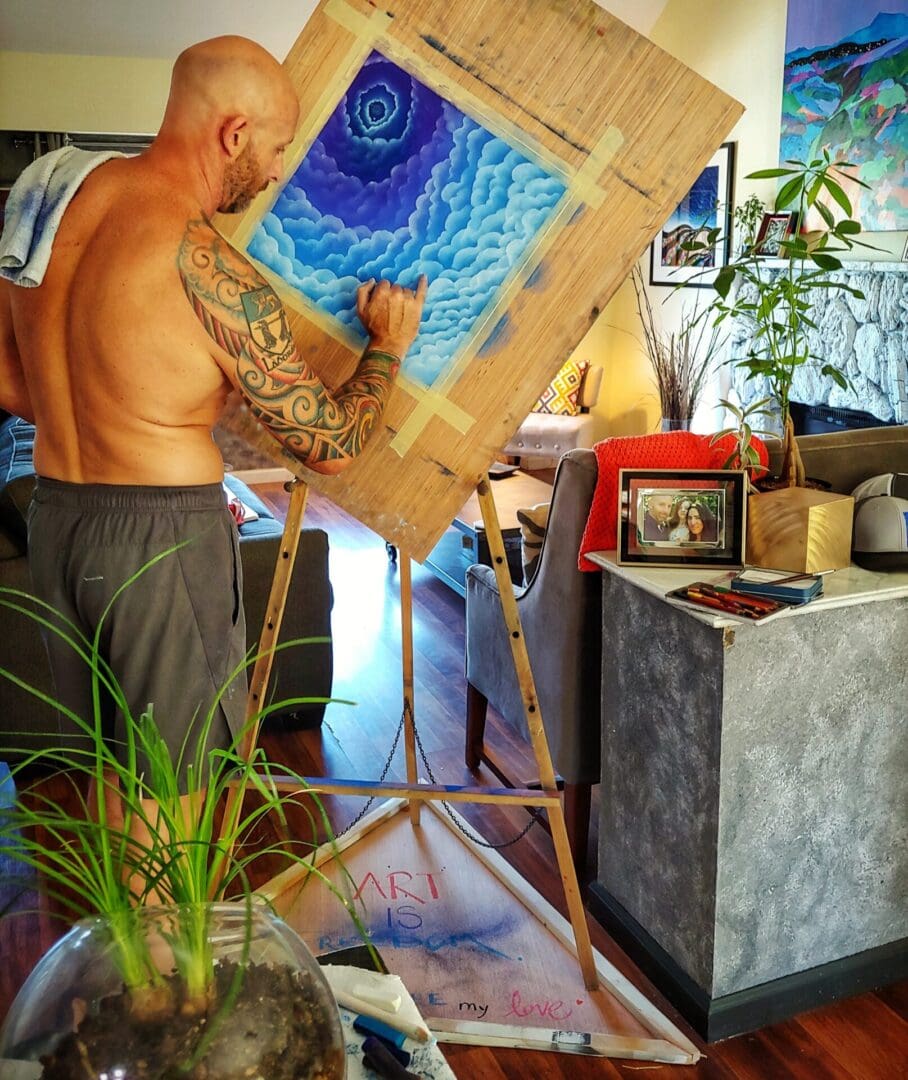 A man painting on canvas in his living room.